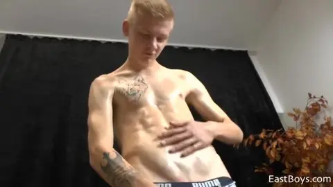 Blonder Twink mit geöltem Körper zeigt sich